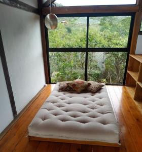 a white tufted couch in a room with a large window at Casa Miralago in Santana do Riacho