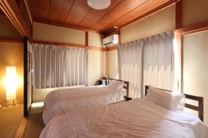 a hotel room with two beds and a window at Guesthouse KEN in Toyama