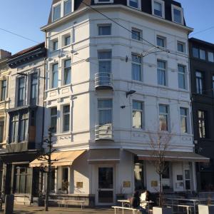 ein weißes Gebäude in einer Stadtstraße mit Tischen in der Unterkunft The Soul Antwerp in Antwerpen