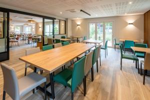 a dining room with wooden tables and green chairs at Sure Hotel by Best Western Tours Sud in Chambray-lès-Tours