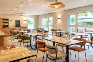 a restaurant with tables and chairs and windows at Sure Hotel by Best Western Tours Sud in Chambray-lès-Tours