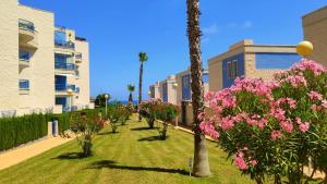 a row of houses with pink flowers and palm trees at Apartamento Punta Glea in Orihuela Costa