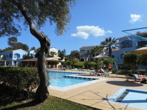 - une piscine avec un arbre à côté d'un bâtiment dans l'établissement Gouvia - Luxury Suite, à Gouviá