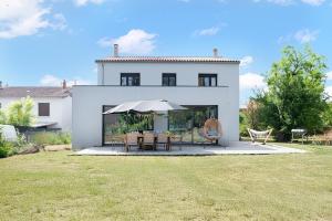 a white house with a table and an umbrella at Villa à Castres, Maison 10 personnes avec piscine privée, jardin et 5 chambres in Castres