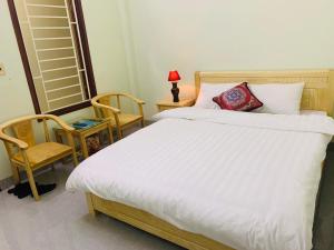 a bedroom with a large white bed and a chair at Tùng Long Hotel in Thanh Hóa +2 photos