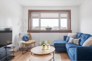 a living room with a blue couch and a table at Braehead Stay - SJA Stays - Modern 2 Bed House in Cruden Bay