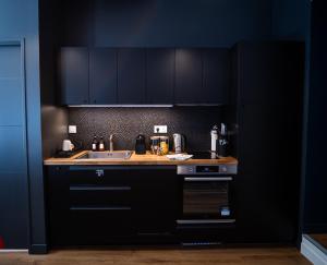 a kitchen with black cabinets and a sink at la Game Room in Pau