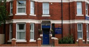 a brick building with a blue door in front of it at The Avenue GuestHouse in Newcastle upon Tyne