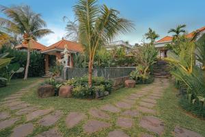 une maison avec des palmiers et une passerelle en pierre dans l'établissement Matahari Lumbung Resort, à Ubud