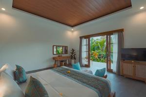 a bedroom with a large bed and a television at Matahari Lumbung Resort in Ubud