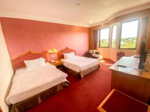 a hotel room with two beds and a television at Parkview Hotel in Kampong Jerudong