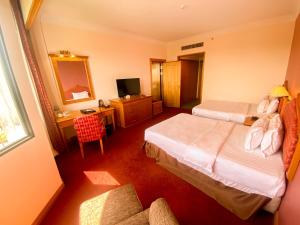 a hotel room with two beds and a desk at Parkview Hotel in Kampong Jerudong