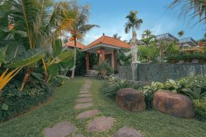 a house with a walkway in front of a yard at Matahari Lumbung Resort in Ubud