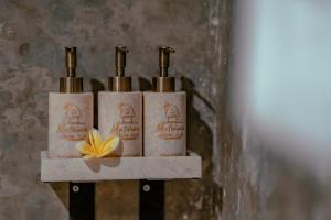 three bottles of soap on a shelf with a flower at Matahari Lumbung Resort in Ubud