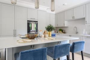 a kitchen with white cabinets and blue chairs at Luxury 3 Bed Penthouse with Large Terrace and Private Parking in Sunningdale +20 photos