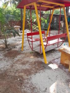 a swing set with two red and yellow poles at Anchor Beach Resort in Diveagar +4 photos