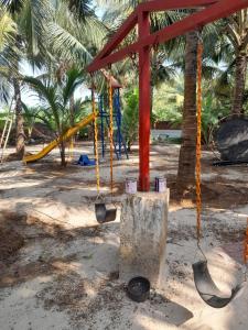 an empty playground with swings and palm trees at Anchor Beach Resort in Diveagar
