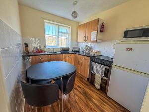 a small kitchen with a table and a refrigerator at 5 Berth Chalet To Hire In Hemsby Near Hemsby Beach Ref 18117B in Hemsby