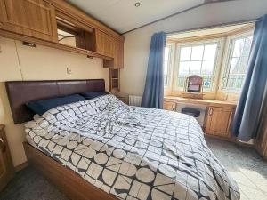 a bedroom with a large bed with blue curtains at Great 4 Berth Caravan For Hire In Suffolk At North Denes, Ref 40149Nd in Lowestoft