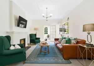 a living room with a brown couch and green chairs at Stylish Apartment, Malvern East in Melbourne