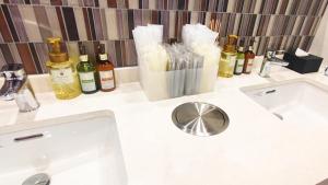 a bathroom counter with a sink and bottles of wine at HOTEL LiVEMAX Honhachinohe Ekimae in Hachinohe +40 photos