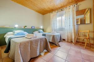 two beds in a room with two tables and a window at Eremita in La Figuera