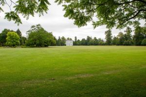 een groot veld met een wit huis in de verte bij Villas at Park Campus in Cheltenham