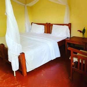 a bedroom with a large bed with white sheets at Nguruma house of travellers and tours in Arusha