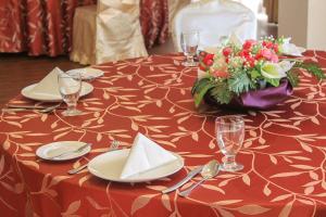 a table with a red table cloth with plates and flowers at Parkview Hotel in Kampong Jerudong +37 photos