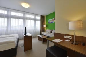 ein Hotelzimmer mit einem Bett und einem Schreibtisch mit einem Computer in der Unterkunft INVITE Hotel Fulda City Hauptbahnhof in Fulda