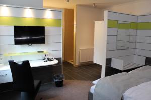 a room with a bed and a desk and a tv at Hotel Ripken in Kirchhatten