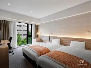 a hotel room with two beds and a desk and a window at Daiwa Roynet Hotel Sendai Ichibancho PREMIER in Sendai
