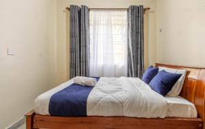 a bedroom with a bed with blue pillows and a window at Bremu Home - Near jkia airport in Nairobi