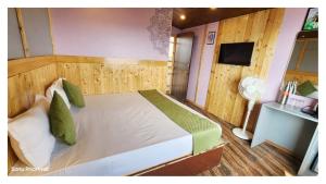 a bedroom with a large white bed with green pillows at Hotel Himaaksh cottages In Sigri in Nainital