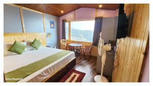 a bedroom with a bed and a television and a table at Hotel Himaaksh cottages In Sigri in Nainital +21 photos
