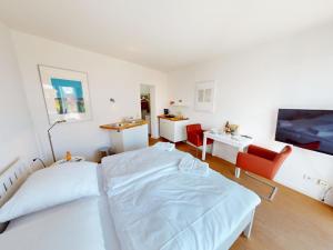 a white bedroom with a bed and a desk at Seehütte - 304 in Cuxhaven