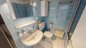 a blue tiled bathroom with a toilet and a sink at Seehütte - 304 in Cuxhaven