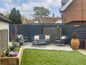 a backyard with chairs and a fence and grass at Corner Cottage in Alburgh