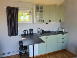 a kitchen with white cabinets and a black counter top at Gäststuga Norafjärden in Sandöverken