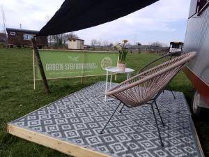 una sedia posta accanto a un tavolo in un campo di Leuke wandel- en fietslocatie vlakbij Zutphen a Vierakker