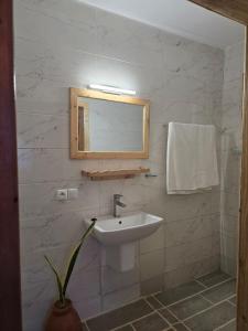 une salle de bain blanche avec un lavabo et un miroir dans l'établissement Oasis Kemba Hôtel-Restaurant-Bar, à Toliara
