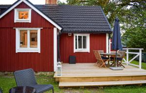 a red house with a deck with a table and chairs at 3 Bedroom Amazing Home In Hallaröd in Hallaröd +11 photos