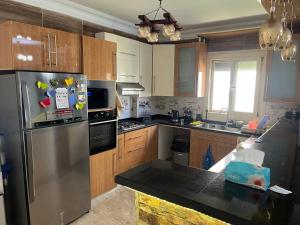 a kitchen with a stainless steel refrigerator and wooden cabinets at Stella villa in El Alamein