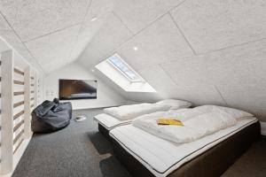 a attic bedroom with two beds and a flat screen tv at Feriehus 1116 in Ringkøbing +35 photos