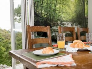 a table with two plates of bread and orange juice at Waterfall Wood Cottage in Patterdale