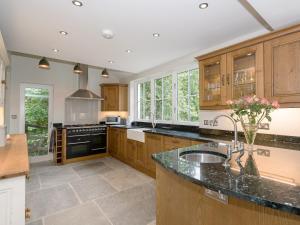 a large kitchen with wooden cabinets and a sink at Waterfall Wood Cottage in Patterdale +21 photos