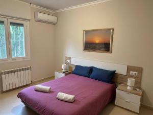 sypialnia z fioletowym łóżkiem z 2 ręcznikami w obiekcie Villa Maja Calpe w mieście Calpe