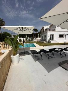 patio z krzesłami, parasolem i basenem w obiekcie Villa Maja Calpe w mieście Calpe
