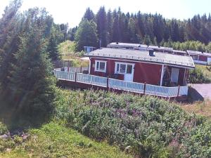 a small red house with a porch on a hill at Sunne Stugcenter 37 in Gräsmark