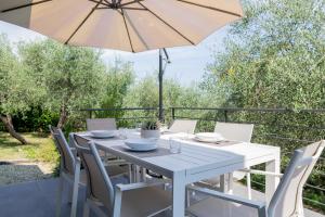 a white table and chairs with an umbrella at TAGGIASCA- Suite nel verde con piscina e terrazza privata in Arma di Taggia